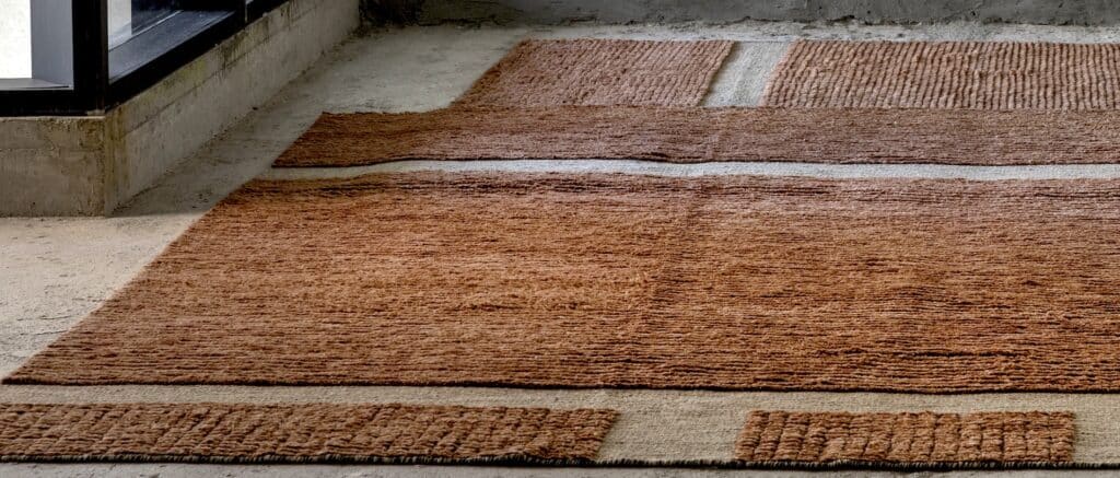 Alfombra de textura gruesa en tonos terracota y cobre sobre un piso de cemento